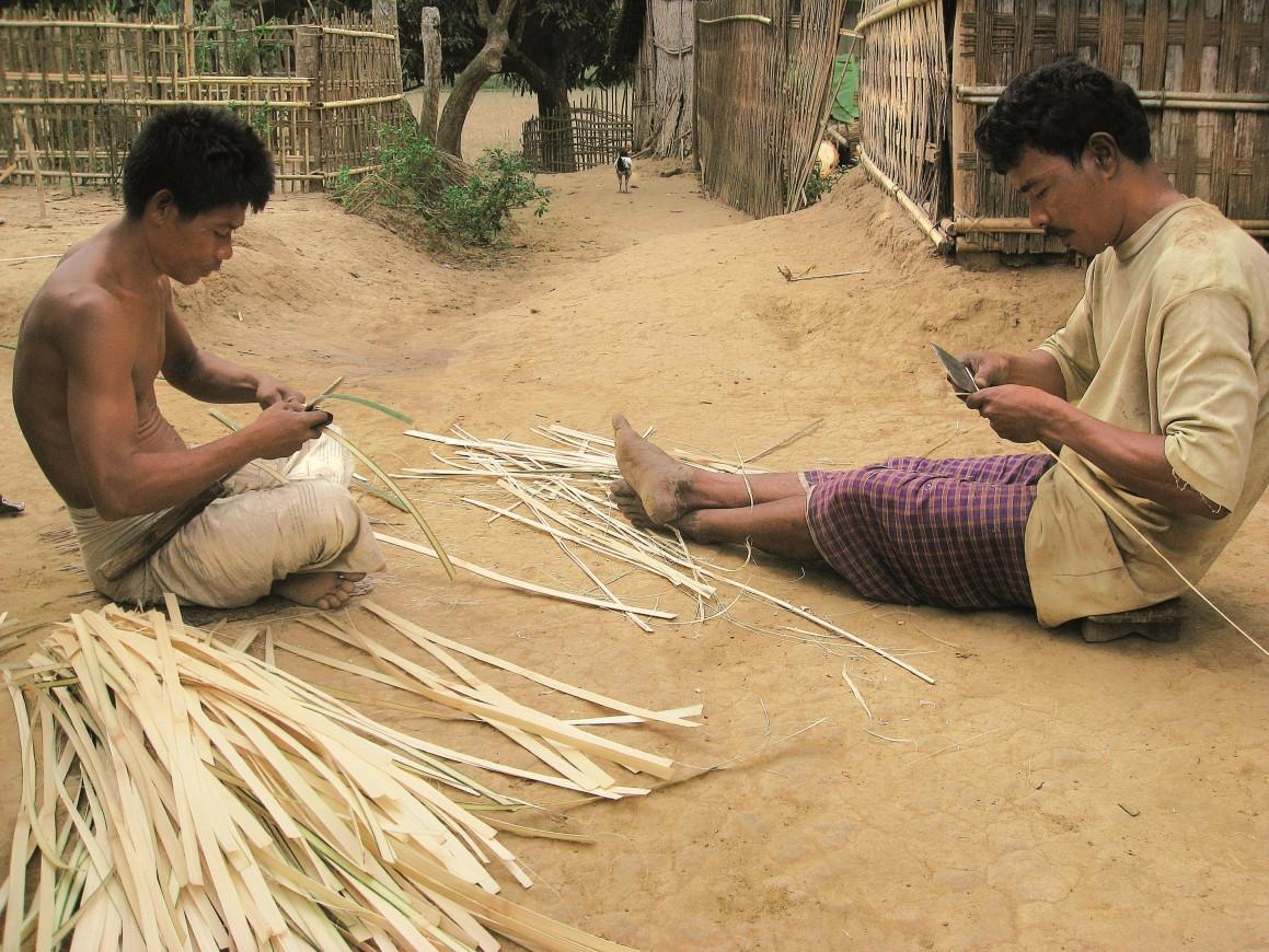 Two men preparing bamboo.