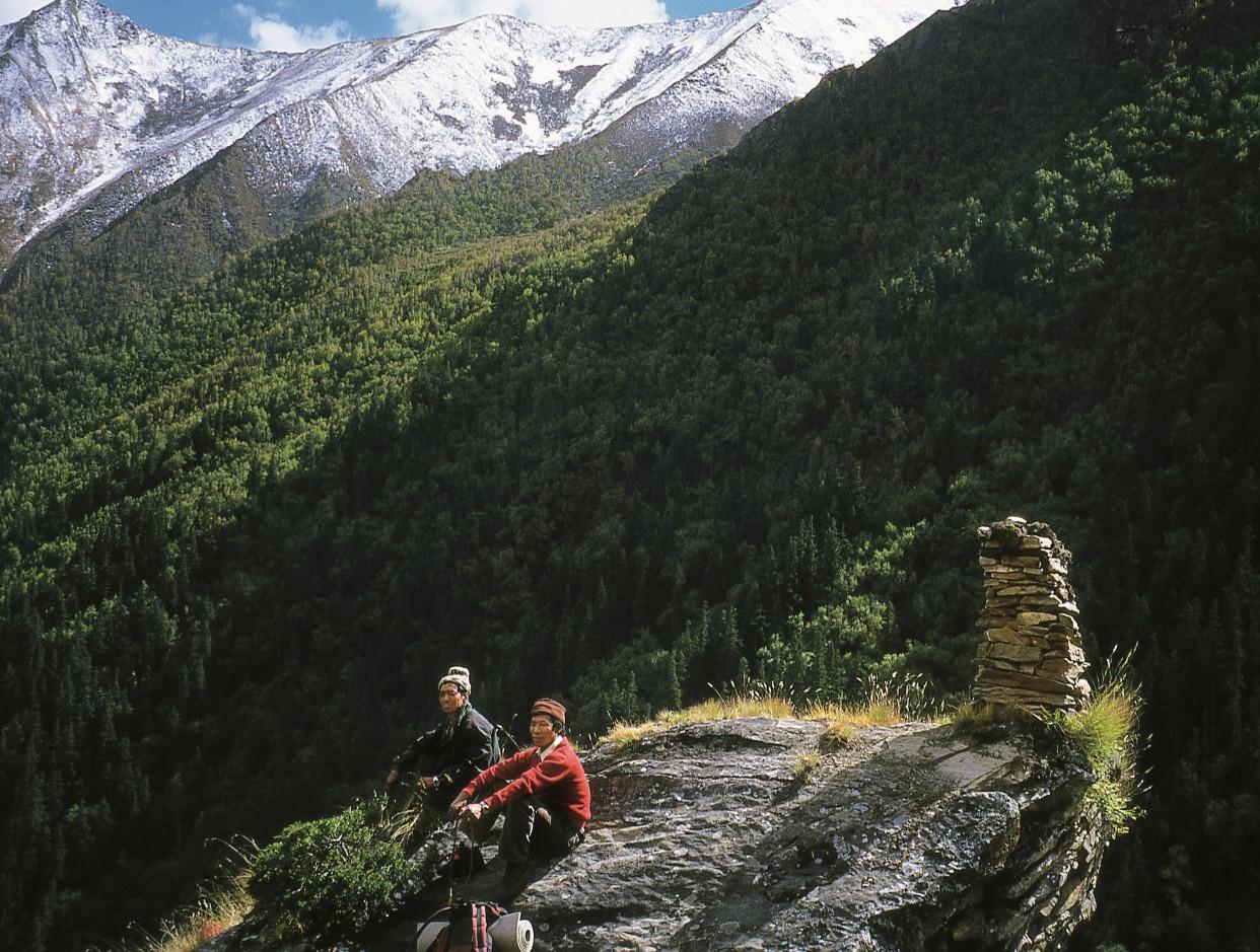 A guard of the Shey Phoksundo National Park and a Tibetan traditional healer converse about the geographical and religious meanings of various territorial markers. The cairn next to them marks out the path for yak herds moving to summer pastures.