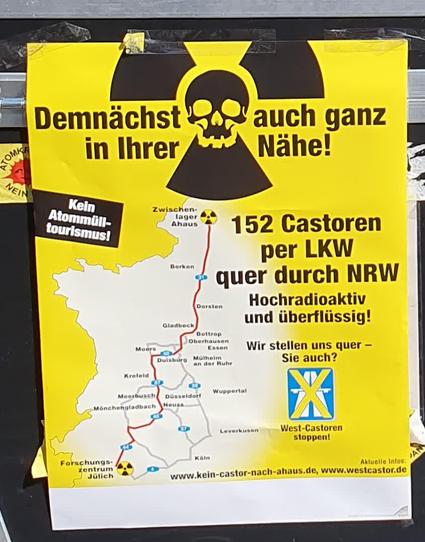 Ein Plakat mit Strahlenwarnzeichen und integriertem Totenkopf und dazu der Text: "Demnächst auch ganz in ihrer Nähe! 152 Castoren per LKW quer durch NRW. Hochradioaktiv und überflüssig! Wir stellen uns quer – Sie auch? Kein Atommüll-Tourismus!www.westcastor.de." Daneben eine Karte mit einer wahrscheinlichen Wegstrecke: Von Jülich u.a. über Mönchengladbach, Krefeld, Duisburg, Gladbeck, Dorsten und Borken nach Ahaus.