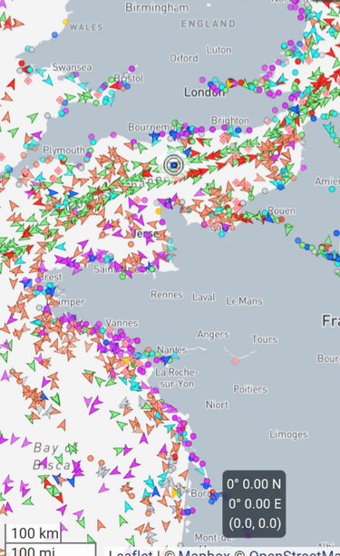 Das Bild zeigt den Screenshot einer Karte mit Großbritannien und Frankreich, wobei die Länder einheitlich grau eingefärbt sind. Auf der  weiß eingefärbten Wasserseite sind hunderte unterschiedlicher eingefärbter spitzwinkliger Dreiecke zu sehen, die jeweils ein anderes Schiff in der aktuellen Position zeigen. Die verschiedenen Farben symbolisieren die diversen Schiffsarten, die Spitze des Dreieck zeigt die Fahrtrichtung.