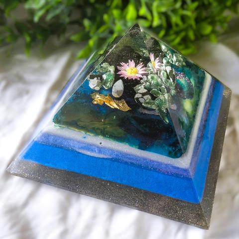 Handgemaakte orgonite piramide van ca. 12x12 cm met bladgoud en metalen, gevuld met sneeuwvlok obsidiaan, groene aventurijn en lavasteen. De piramide straalt een krachtige, harmoniserende energie uit.

#orgonites #orgonitepiramides