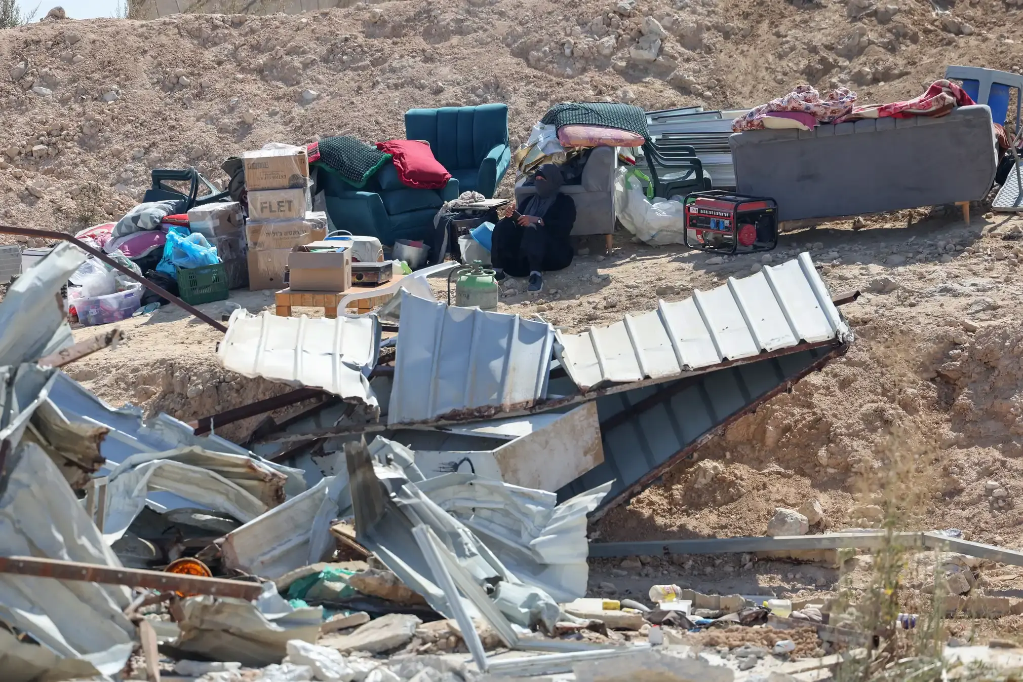 A Bedouin woman sits next to her belongings at the site where a house was demolished by Israeli forces in the Negev desert.