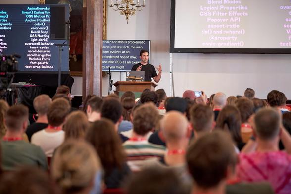 Me on stage, viewed from afar with a truckload of modern CSS properties and functions on the screen behind me.