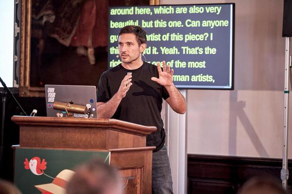 Matthias on stage at Smashing Conf Freiburg, talking to the audience, with a monitor behind me displaying live captions.