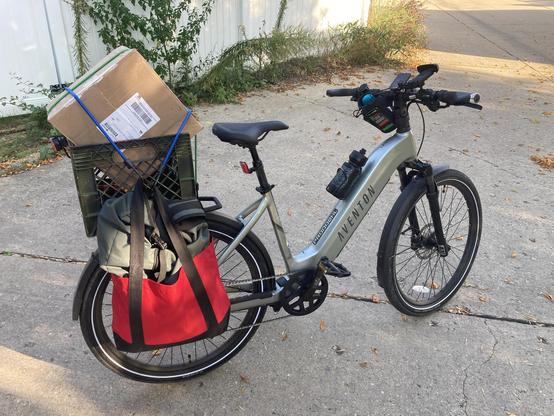 An ebike with a large box in a crate on the rack and a DIY pannier.