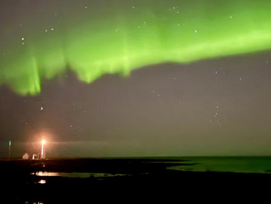 A line of green aurora goes over Grótta lighthouse