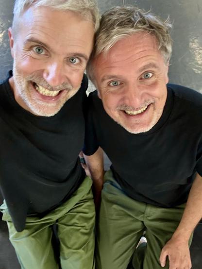 François et Christian se ressemblent étrangement. Ils ne sont pas jumeaux, mais arborent la même chevelure argentée qui se reflète dans leurs grands yeux bleus. Ils étincellent du même sourire... et de la même barbe de trois jours. Aujourd'hui, la ressemblance est poussée à l'extrême. Tous deux portent des pantalons de coton verts, et un t-shirt noir... La photo est cadrée en selfie, depuis le haut. 