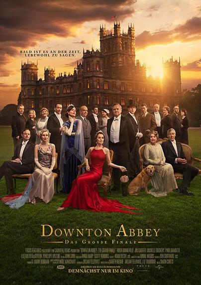 Das Filmplakat zeigt die Hauptfiguren von Downton Abbey in eleganter Abendgarderobe, die vor einem prachtvollen Schloss bei Sonnenuntergang posieren. Im Zentrum sitzt eine Frau in einem auffälligen roten Kleid, umgeben von weiteren Figuren in festlicher Kleidung. Ein Hund liegt zu ihren Füßen. Über dem Schloss steht der Schriftzug: „Bald ist es an der Zeit, Lebwohl zu sagen.“ Unten im Bild befindet sich der Titel „Downton Abbey – Das große Finale“ in goldener Schrift. Darunter der Hinweis: „Demnächst nur im Kino“.