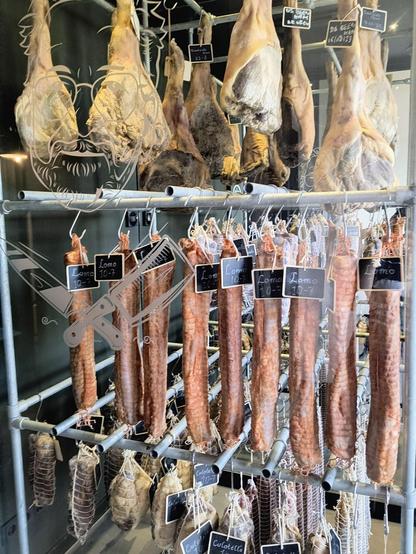 Zu sehen ist der gläserne Fleischtrockenschrank im Restaurant Dockside der voller Schinken, Würste und Fleischstücke hängt.
