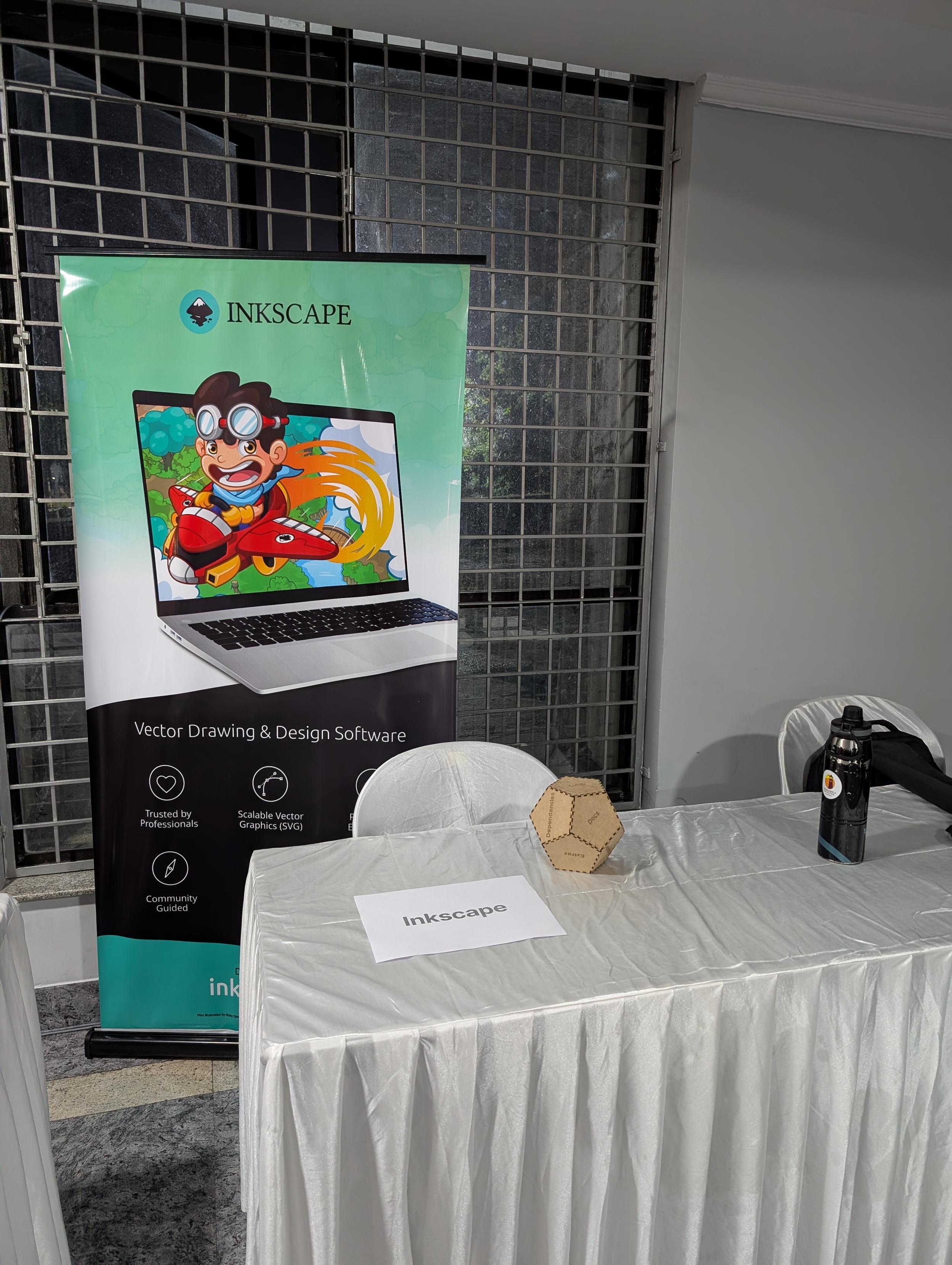 A picture of the Inkscape booth at IndiaFOSS2025 showing a standee, a paper with Inkscape written on it, and a laser cut dice made with Inkscape. A picture of the Inkscape booth at IndiaFOSS2025 showing a standee, a paper with Inkscape written on it, and a laser cut dice made with Inkscape.
