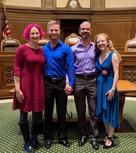 Casey and Daniel stand side by side holding hands, smiling after being legally married. On Casey's right is his BFF Jonobie. On Daniel's left is his very dear friends Rachel.