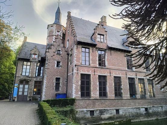 Zu sehen ist das  Wasserschloss, gebaut aus roten Klinkersteinen mit einem Wohnturm an der linken Giebelseite. Das Gebäude ist zwei Stockwerke hoch und hat ein Spitzdach  an dem auch ummauerte Giebelfenster zu sehen sind