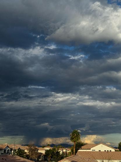 White tops and dark blue bottoms of scattered clouds across the sky. With much taller clouds somewhere far on the horizon. They like completely sitting on the ground.