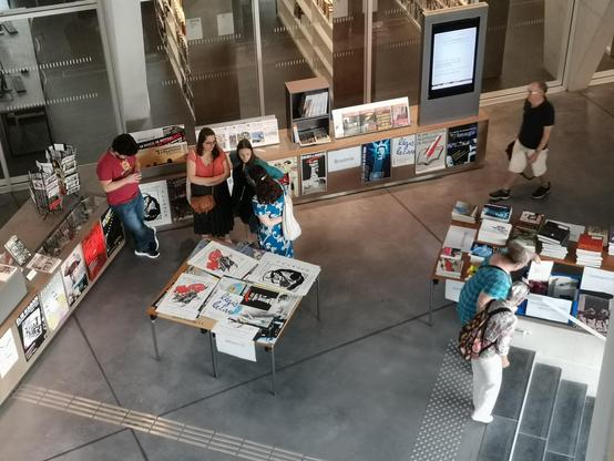Le public à l'accueil de La Contemporaine rassemblé autour de nombreux goodies prêts à la vente !