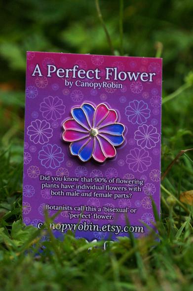 a flower enamel pin in bisexual colours. It is on a backing card which reads "A perfect flower by canopy robin. Did you know that 90% of flowering plants have individual flowers with both male and female parts. botanists call this a bisexual or perfect flower."