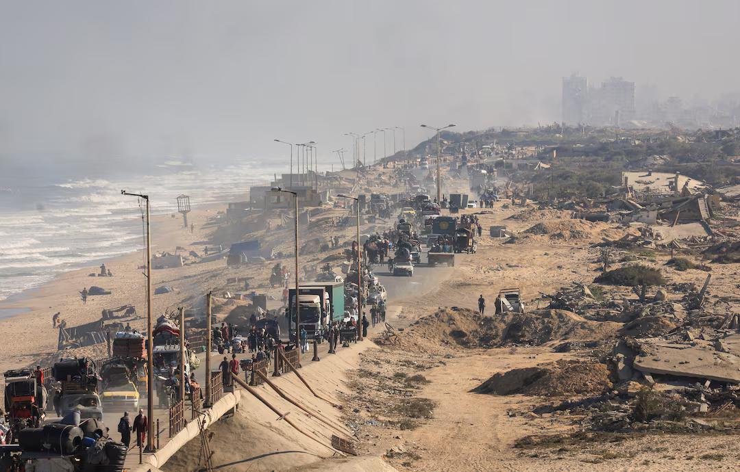 A long convoy of forcefully displaced people heading south on the beachside road, the other one is blocked by earth berms. A long convoy of forcefully displaced people heading south on the beachside road, the other one is blocked by earth berms.