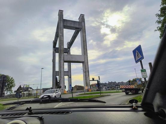 Zu sehen ist eine Hubbrücke in Belgien, in der Mitte des Bildes, davor einen Verkehrskreisel. Rechts ist ein Fußgängerüberweg-Schild zu sehen, auf dem, statt einem Fußgänger ein Radfahrer zu sehen ist.