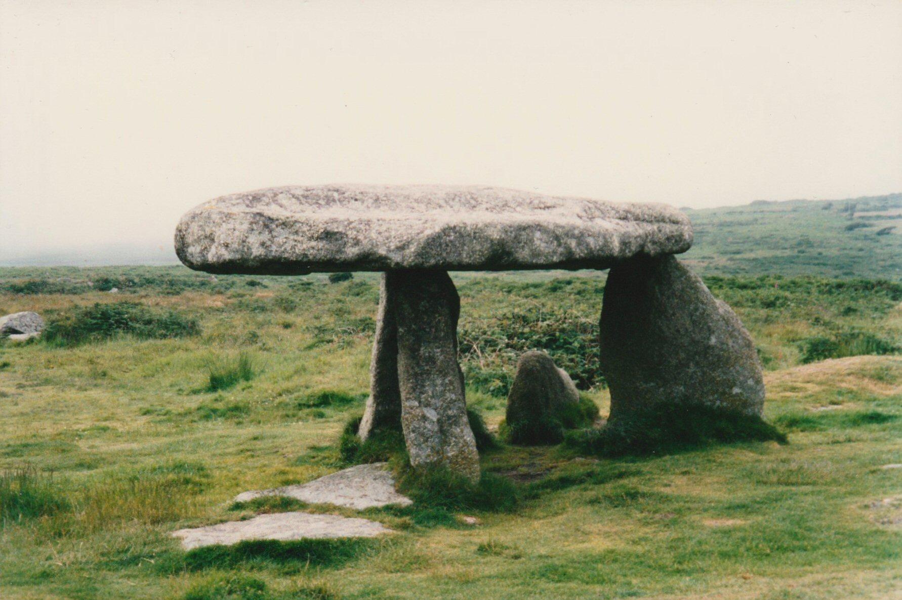 Colour photo of Lanyon Quoit in Cornwall, a portal tomb or dolmen on the moors of West Penwith, taken in July 1993. The three remaining uprights support a capstone weighing some 12 tonnes, and is about 5陆m long. The monument is surrounded by moorland and green vegetation and the moors in the background are covered in dense fog.