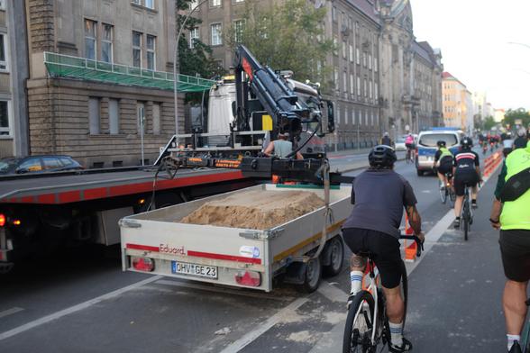 Abschlepp-LKW nimmt einen PKW-Anhänger mit einem Sandberg auf den Kran.