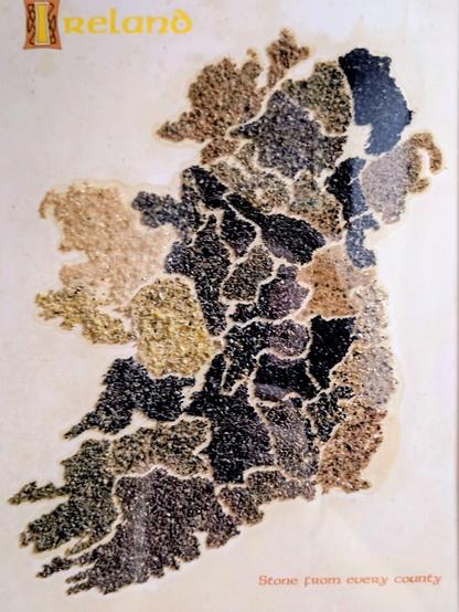 Zu sehen ist eine stilisierte Karte von Irland, bei der die Countys mit unterschiedlich farbigen Steinen aus den jeweiligen County dargestellt ist