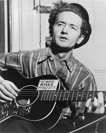 woody guthrie with his guitar
