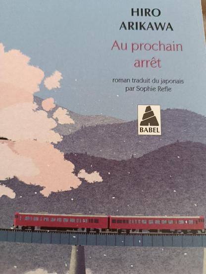 Couverture du livre Au prochain arrêt de Hiro Arikawa. Un train passe sur un pont, un cerisier japonais délivre ses pétales.
