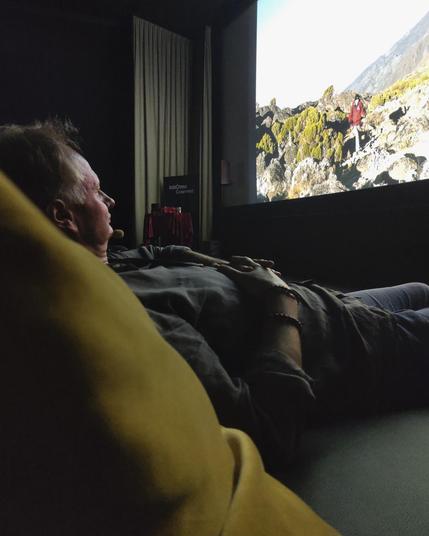 Michael im Kinosessel liegend vor der Leinwand