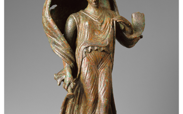 This Roman bronze statuette depicts a female figure suspended in the air with her toes pointed as if about to land. Her right hand grasps an object that is difficult to identify. It might be an alabastron, a small vessel for precious liquids, or it may be the end of a short, down-turned torch. The windblown mantle and the alighting posture characterise the figure as a personification of nature, especially the celestial forces. Her attribute, either a torch, or perhaps a vessel of dew or dreams,…