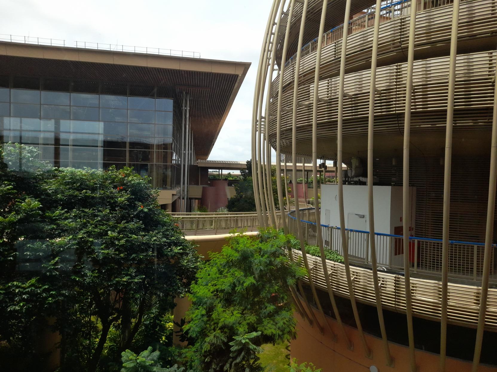 Yet another view of part of an outdoor garden as seen from the upper level of Terminal 2 of Bangalore's Kempegowda International Airport. On the right of the garden is a pavilion with elevated walkways connecting the terminal building to it.