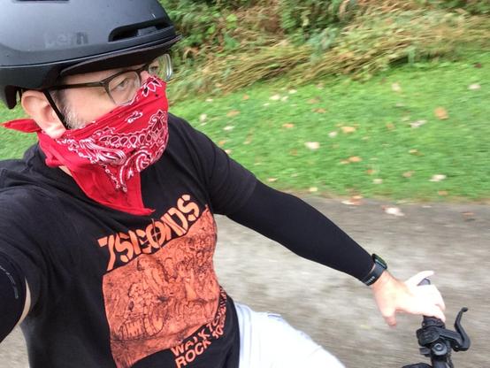 A human person on a bike with a bandana and arm sleeves. 
