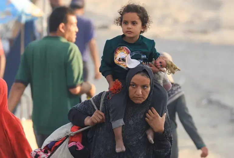 A woman carries her daughter on her shoulders.