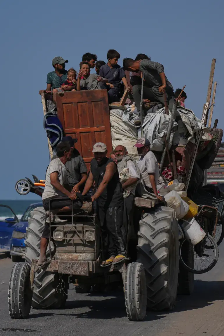 Dozens of people flee on an overloaded tractor.