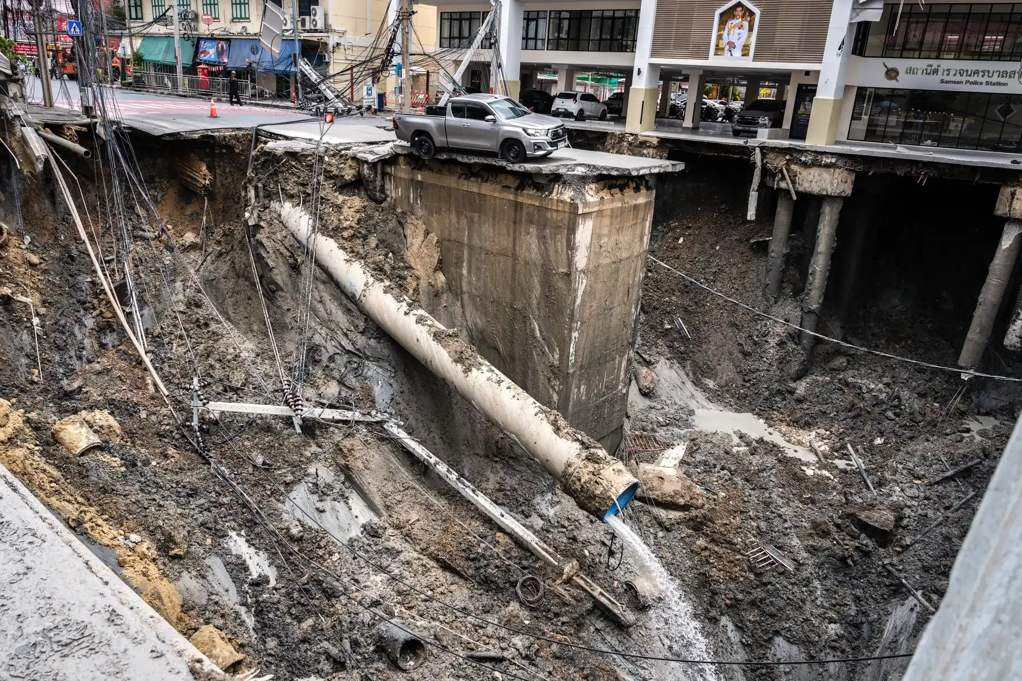 A car is parked on a column in the midst of a sinkhole.