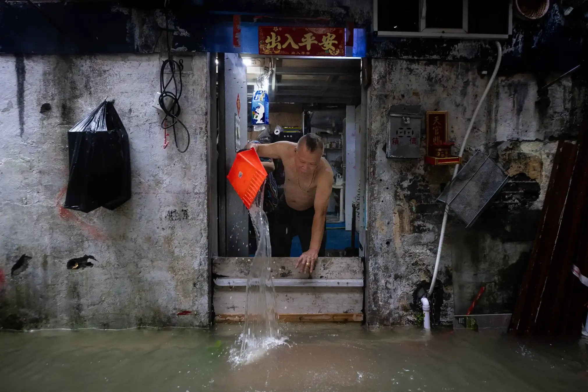 A man bails water from his home.