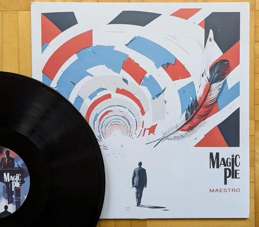 Eine Schallplatte mit dem Titel "Maestro" von Magic Pie liegt neben ihrem abstrakten Cover aus, das spiralförmige Muster in Rot, Weiß und Blau sowie eine Feder und die Silhouette einer Person zeigt, die sich entfernt. Der Hintergrund ist aus Holz.