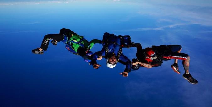 Upside down picture of three skydivers in freefall. (Photo via Skydive California).
