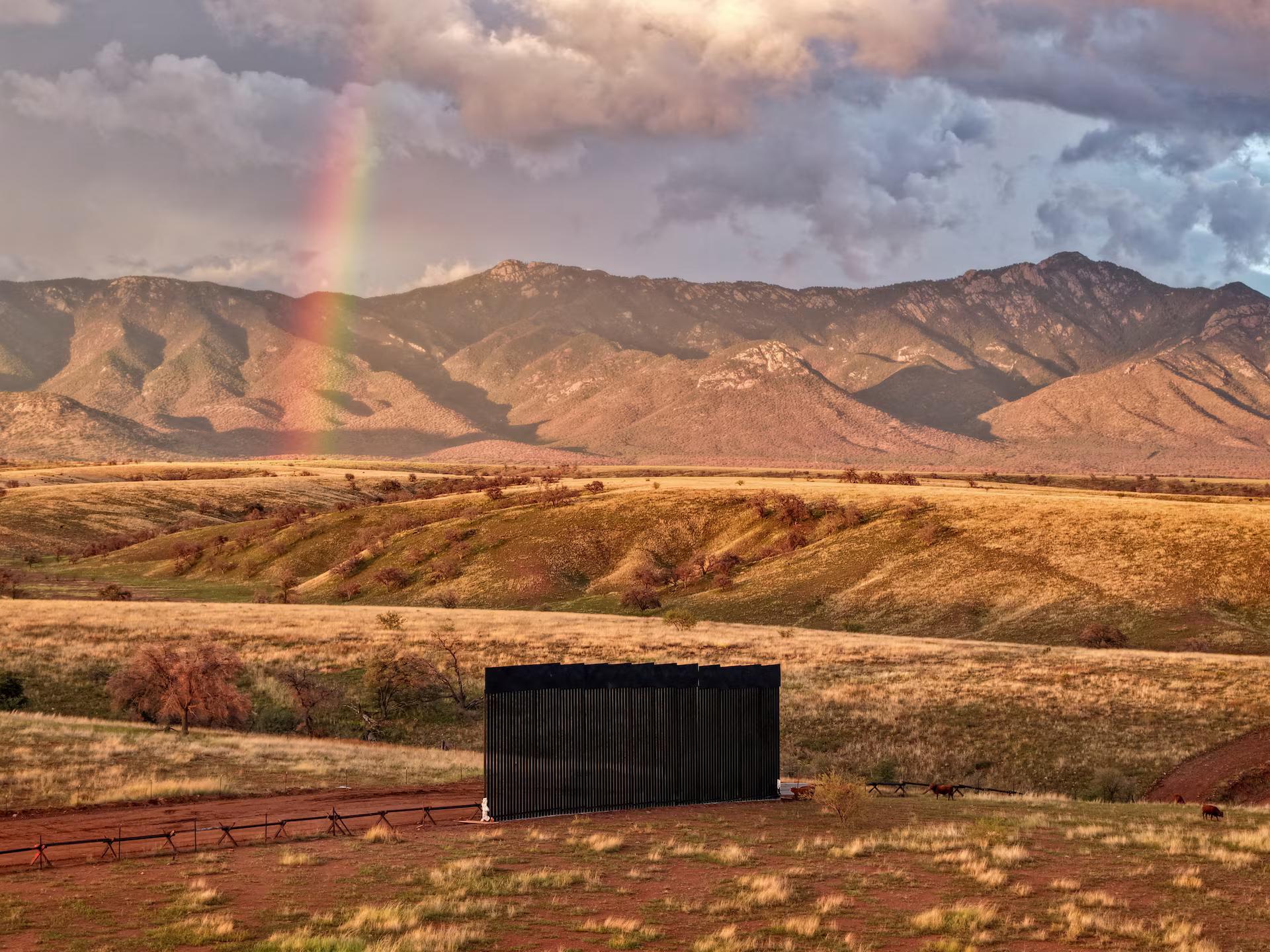 A drone view shows a new section of the border wall that stands in Arizona's San Rafael Valley, with a rainbow in the background.