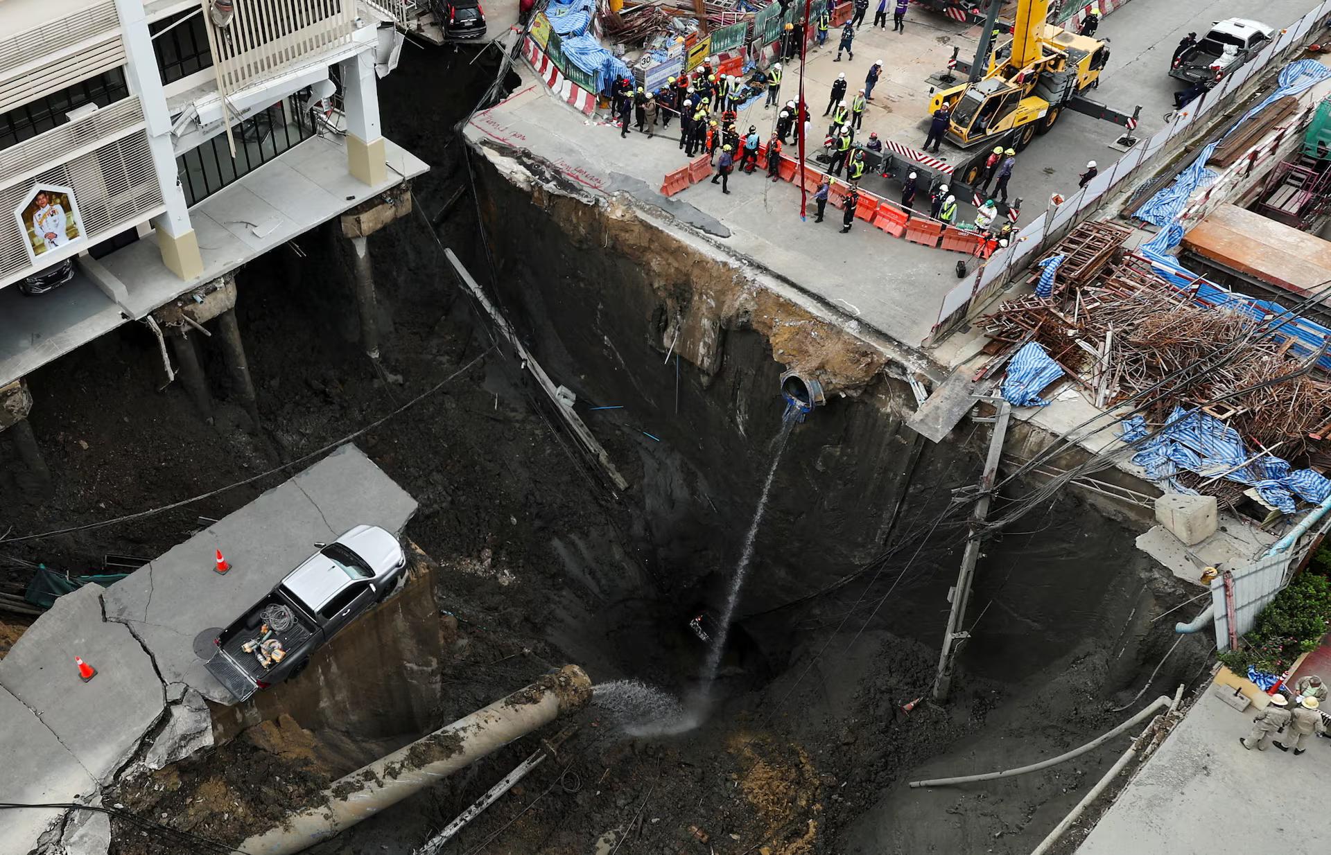 A vehicle teeters on the edge of a massive sinkhole that opened on Samsen Road near Vajira Hospital, in Bangkok