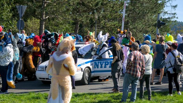 Orni Fursuiter in einer Gruppe andere Fursuiter an einem Polizeiwagen