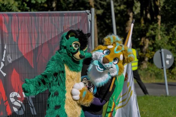 Grüner Katzenfursuiter posiert mit Hunde Fursuiter
