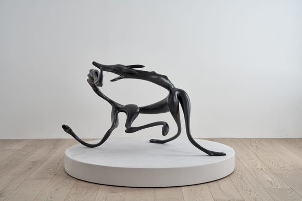 Abstract sculpture of a dog spinning to catch its tail, evocative of the movement of this playful moment.