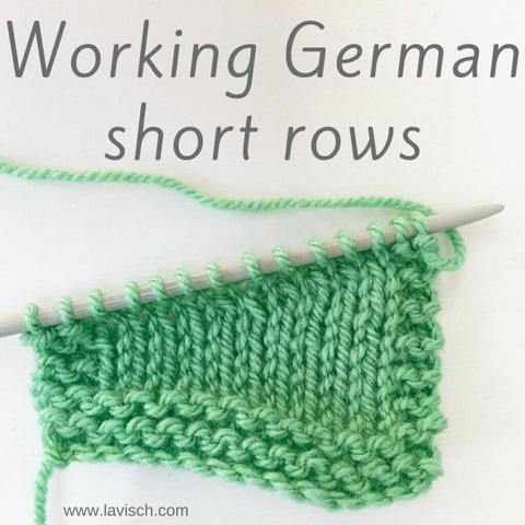 A knitted swatch in mint green yarn on a gray knitting needle in which some shaping has been worked with German short rows.
