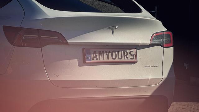 Rückseite eines weißen Teslas mit dem dänischen Kennzeichen „AMYOURS“.