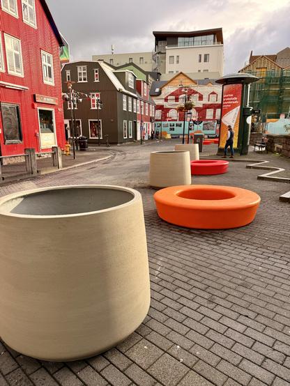 Some planters and donut shaped benches are placed in parking spaces adjacent to Ingolfstorg 