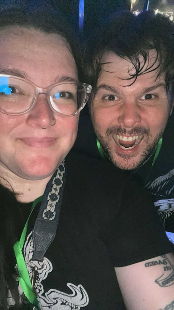 A woman and man pose for a selfie. The man is bearded and excited. The woman is smiling. Both are immensely sweaty.