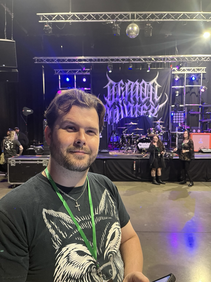 A man stands in front of Demon Hunter’s stage set before the show begins