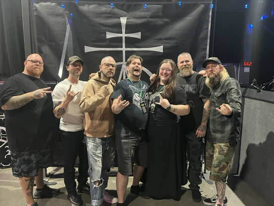 The five members of the Christian Metal band Demon Hunter pose with fans, a man and woman. 