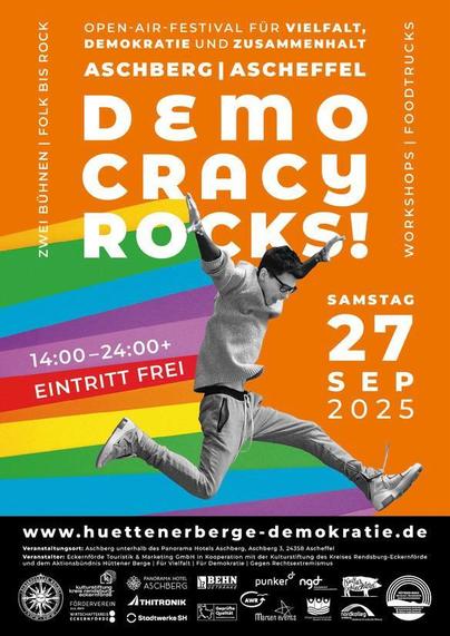 Das Plakat für das Open-Air-Festival „Democracy Rocks!“ am Samstag, 27. September 2025 in Aschberg/Ascheffel. Buntes Design mit Regenbogenfarben, tanzender Person in Schwarz-Weiß. 
Infos: zwei Bühnen (Folk bis Rock), Workshops, Foodtrucks, Eintritt frei, 
Uhrzeit 14:00–24:00 Uhr. 
Slogan: „Für Vielfalt, Demokratie und Zusammenhalt“. 
Website: huettenerberge-demokratie.de.