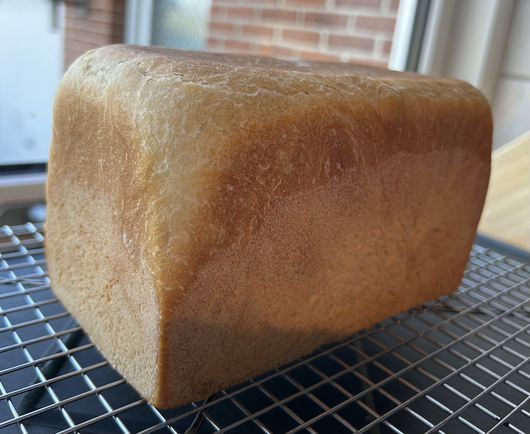 A loaf of fresh baked sourdough bread that is square in profile because it has been baked in a Pullman tin