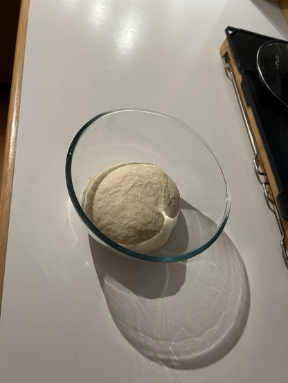 A ball of sourdough bread dough sitting in a glass bowl, ready for first proof